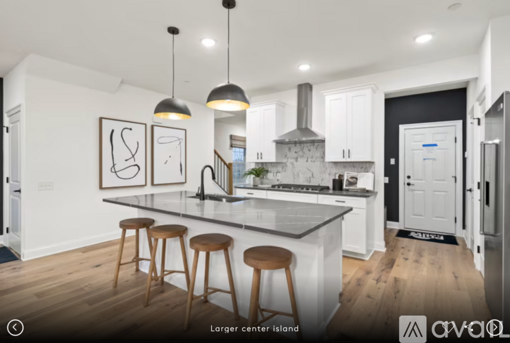 A kitchen with white cabinets and a large island with three stools.