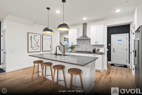 A kitchen with white cabinets and a large island with three stools.