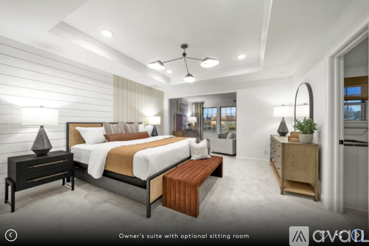 A bedroom with a bed, bench, and optional sitting room.