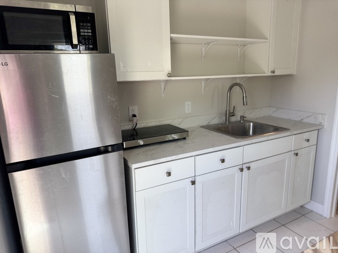A kitchen with a stainless steel refrigerator and white cabinets.
