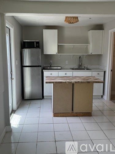 A kitchen with a refrigerator, sink, and cabinets.