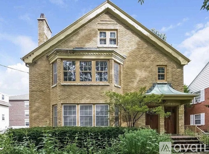 A two-story house with a green roof and a brick exterior.
