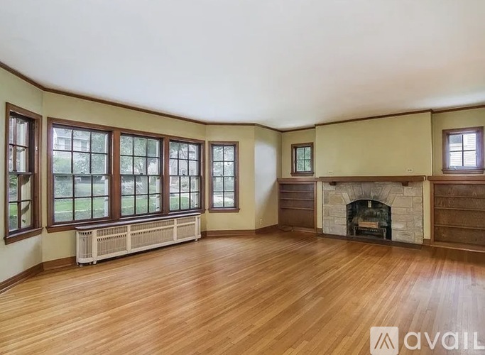 A spacious room with a fireplace and wooden floors.