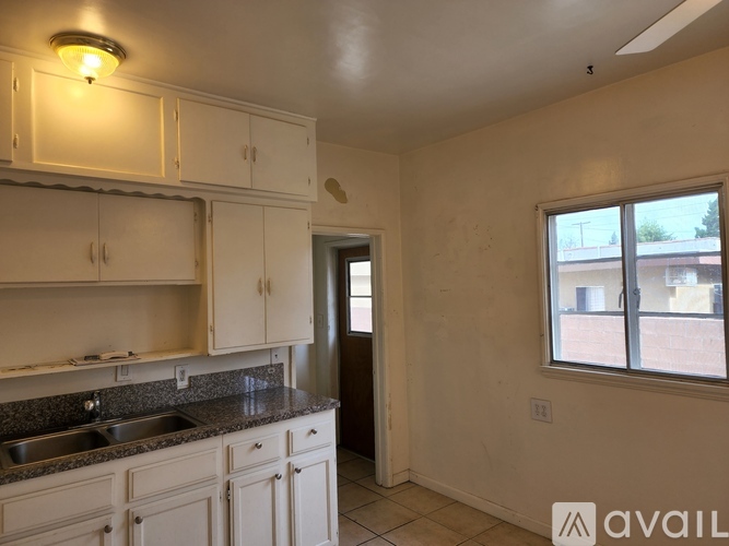 A kitchen with white cabinets and a window overlooking a building.