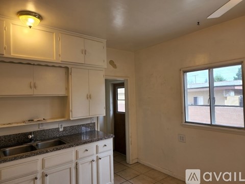 A kitchen with white cabinets and a window overlooking a building.