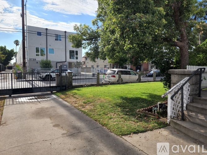 A building with the number 3728 on it is surrounded by a fence and has a tree in front of it.