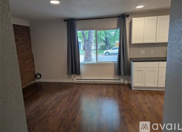 A room with wooden floors and a window with curtains.