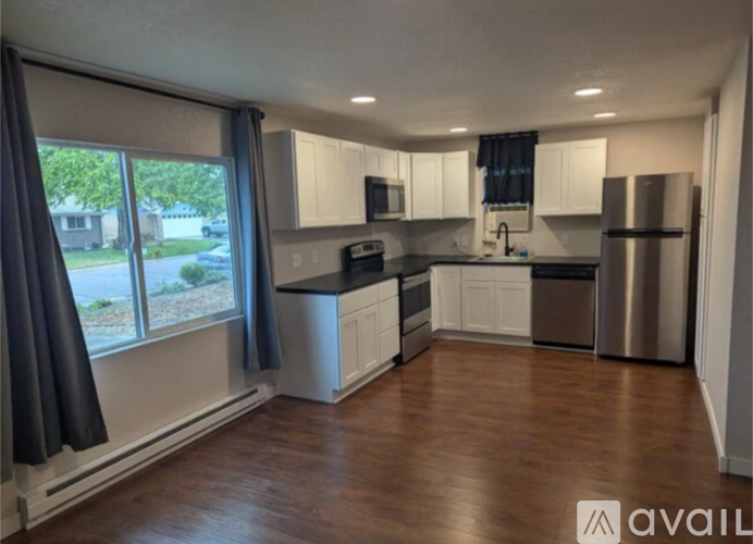 A kitchen with white cabinets and a wooden floor.
