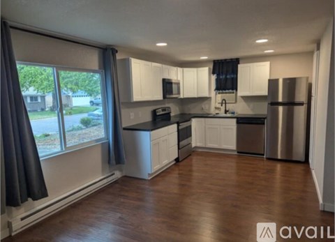 A kitchen with white cabinets and a wooden floor.