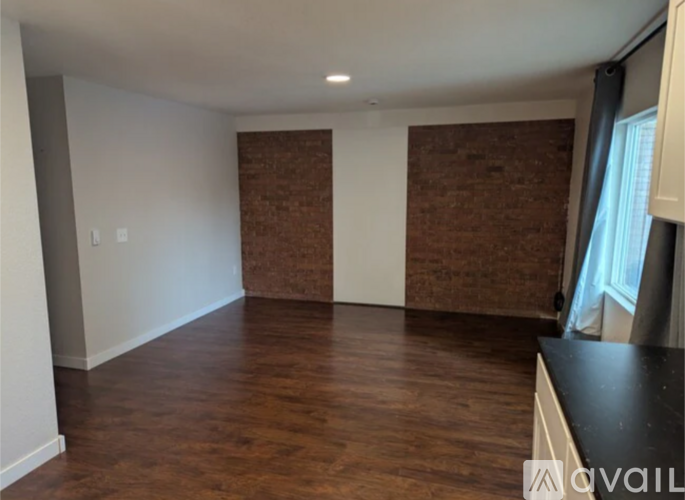 A room with wooden floors and a brick wall.