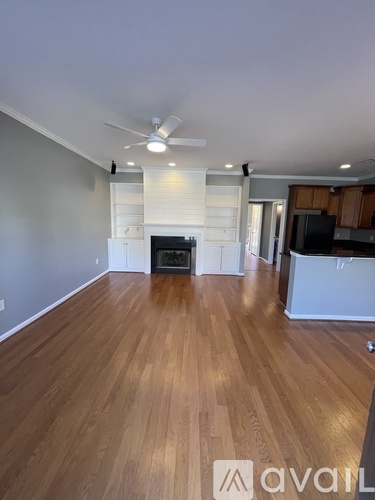A spacious room with wooden flooring and a ceiling fan.