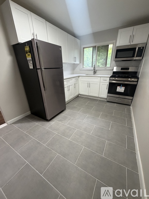 A kitchen with a black fridge and white cabinets.