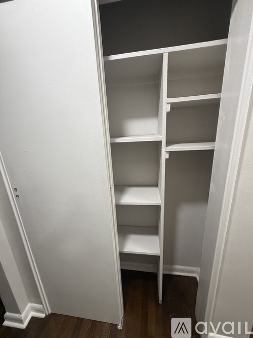 A white shelving unit with four shelves is in a room with white walls.