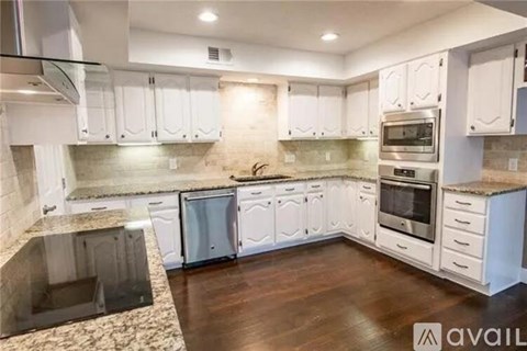 A kitchen with white cabinets and a granite countertop.