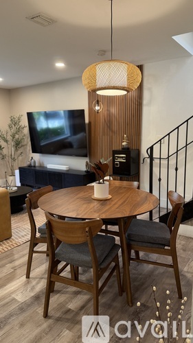 A modern dining room with a round wooden table and chairs.