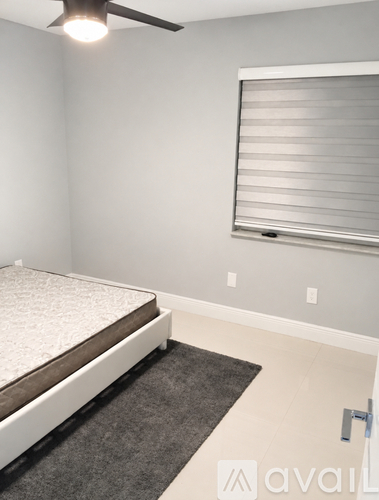 A bedroom with a bed, window with blinds, and a ceiling fan.
