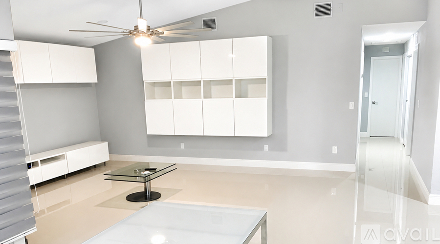 A spacious room with a glass table and white cabinetry.
