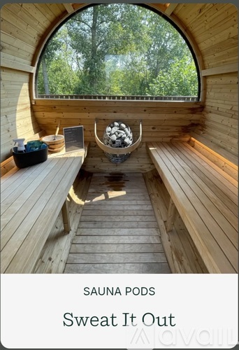 A wooden sauna pod with a view of trees outside the window.