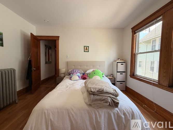 A bedroom with a bed, a nightstand, and a window.