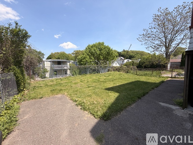 A gravel path leads through a grassy area with a fence and trees.