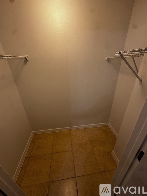 A small, empty room with a tiled floor and two shelves on the wall.