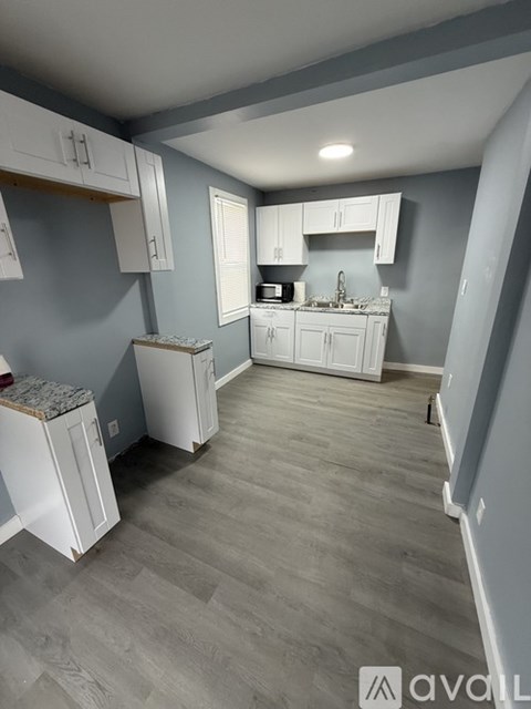 A kitchen with white cabinets and a grey floor.