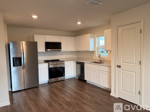 A kitchen with white cabinets and a stainless steel refrigerator.