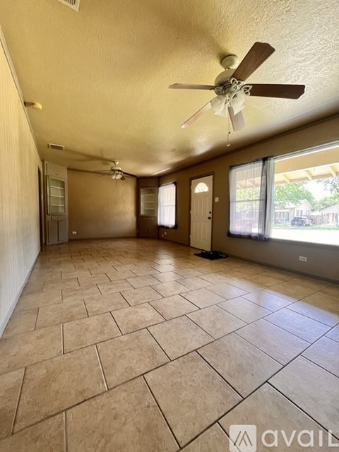 A spacious room with tile flooring and a ceiling fan.