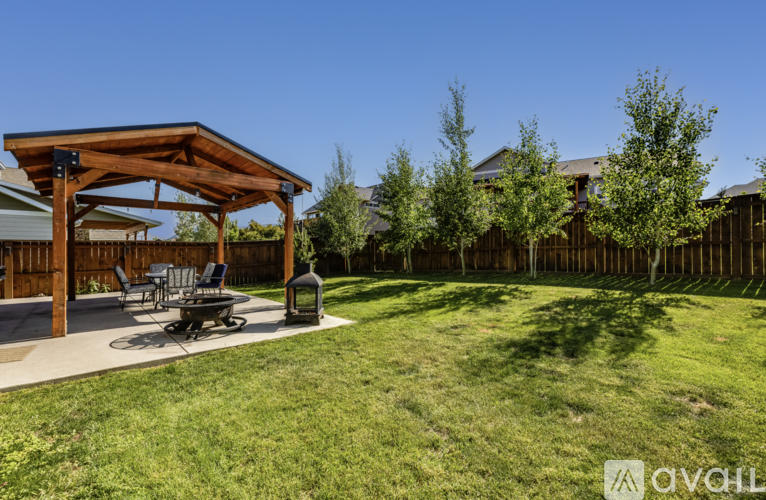 A wooden pergola is situated in a grassy backyard.