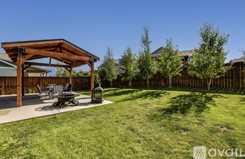 A wooden pergola is situated in a grassy backyard.