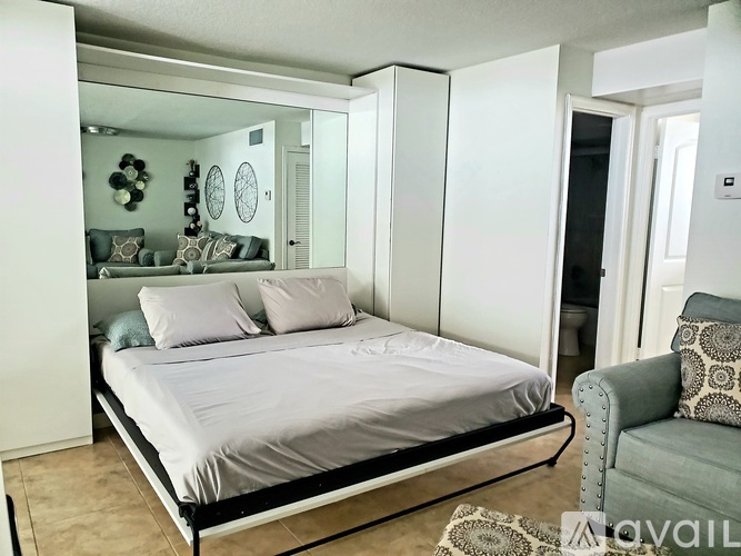 A bedroom with a bed, a chair, and a mirror on the wall.