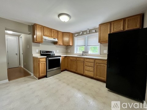 A kitchen with wooden cabinets and a black refrigerator.