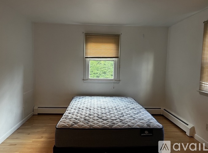 A bedroom with a bed, window, and wooden floors.