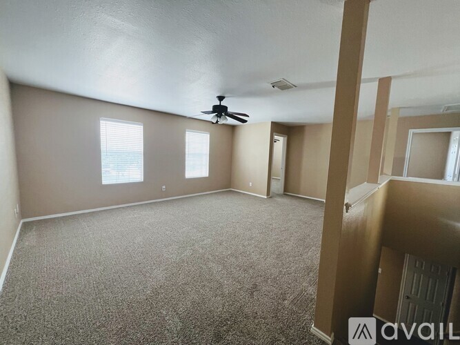 A spacious room with a carpeted floor and a ceiling fan.