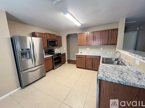 A kitchen with a refrigerator, microwave, oven, sink and cabinets.