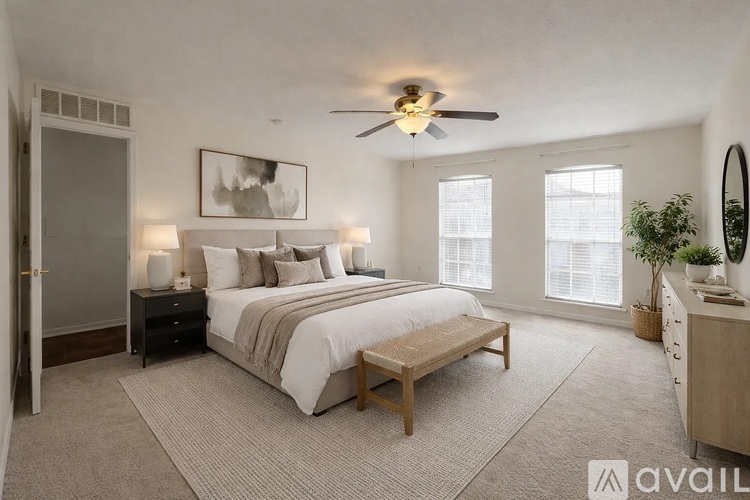 A well-lit bedroom with a large bed, a bench, and a ceiling fan.