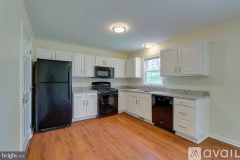 A kitchen with white cabinets and a black fridge.