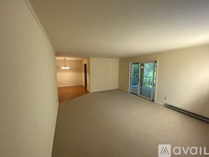 A spacious room with a carpeted floor and a sliding glass door leading to a balcony.