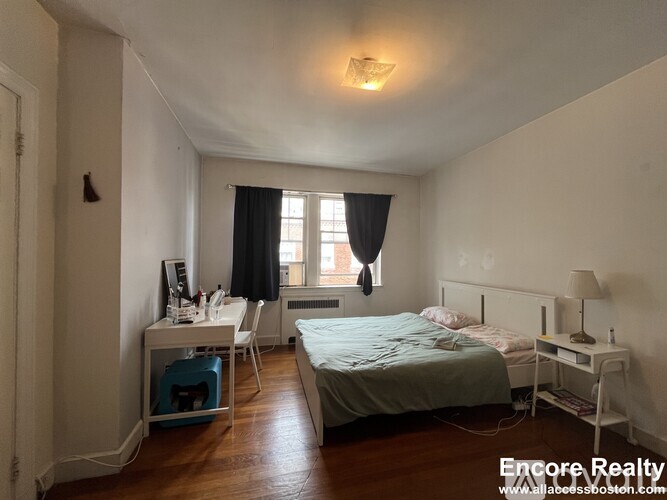 A bedroom with a bed, desk, and chair.