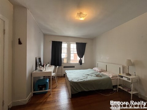 A bedroom with a bed, desk, and chair.