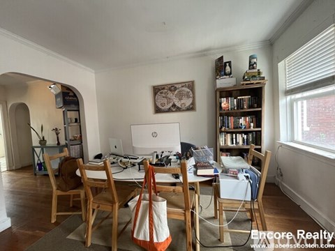 A dining room with a table, chairs, and a bookshelf.