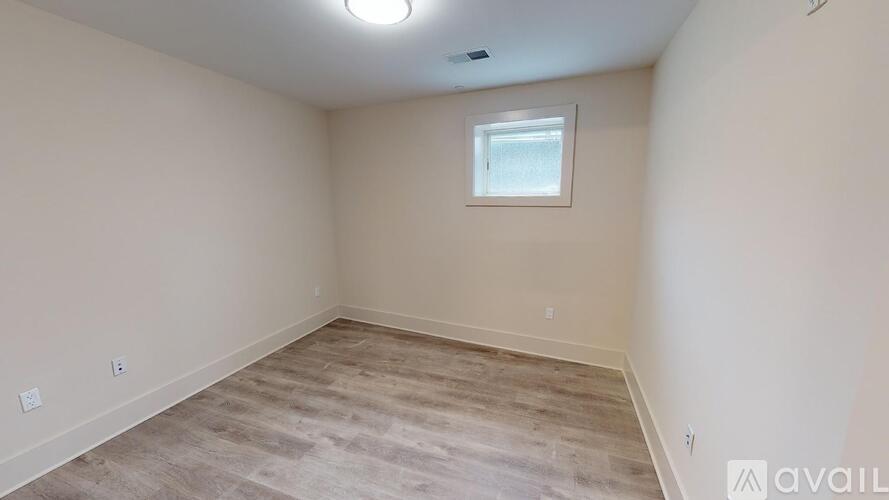 A room with a window and a wooden floor is available for rent.