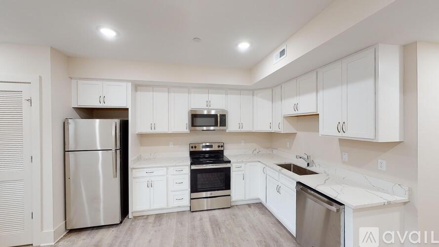 A modern kitchen with white cabinets and stainless steel appliances.