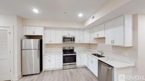 A modern kitchen with white cabinets and stainless steel appliances.