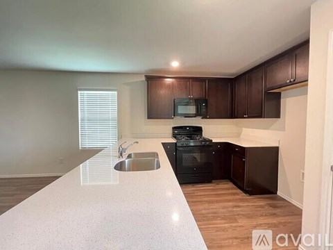 A kitchen with a white countertop and dark brown cabinets.