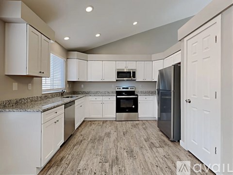 A kitchen with white cabinets and a wooden floor.