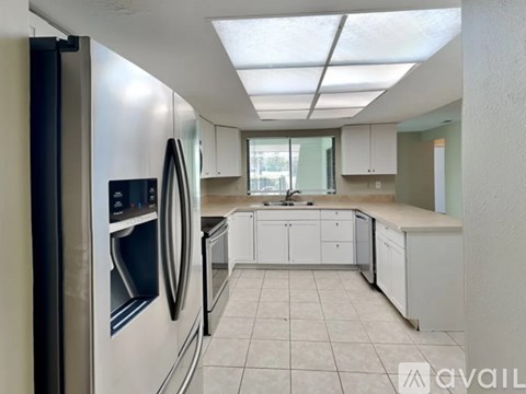 A kitchen with white cabinets and a stainless steel refrigerator.