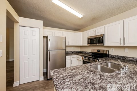 A kitchen with a granite counter top and stainless steel appliances.
