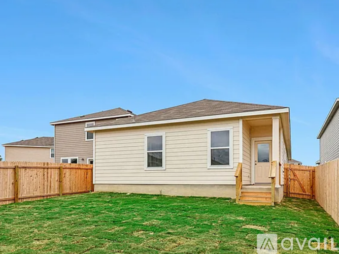 A beige house with a brown fence and a green lawn.