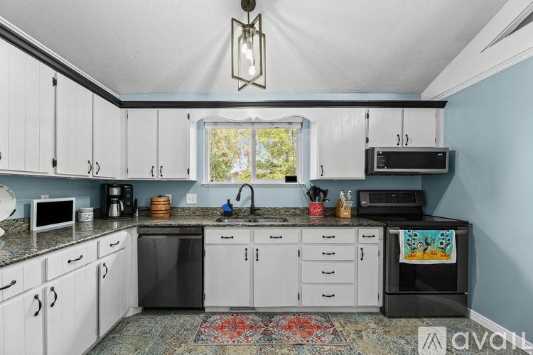 A kitchen with white cabinets and a black dishwasher.